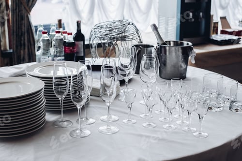 Preview: Assortment of kitchenware on white table.View over white round table with stacks of white plates