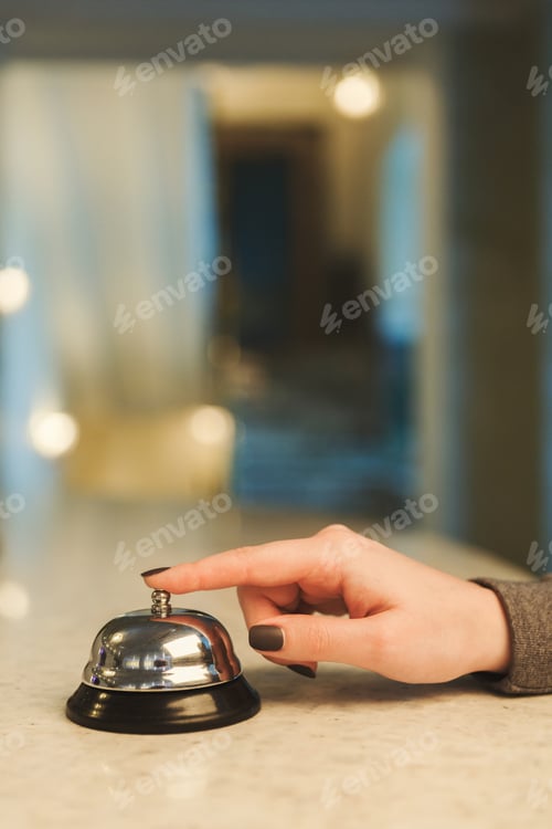 Preview: Woman ringing hotel reception service bell closeup
