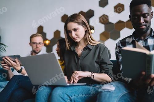 Preview: Thoughtful woman browsing laptop and sitting with group of people
