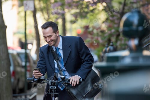 Preview: A man in a business suit, wheeling a bicycle, with a cycle helmet in his hands.