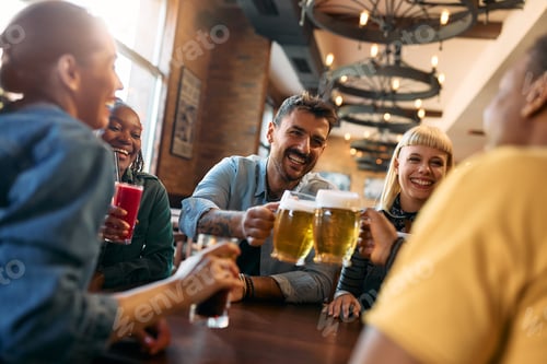 Preview: Cheerful group of friends toasting while gathering in a pub.