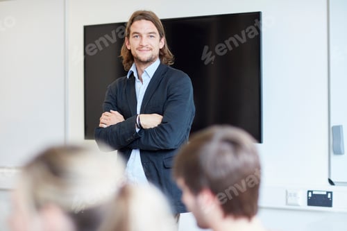Preview: Portrait of male lecturer with arms folded in higher education college classroom