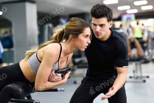 Personal trainer helping young woman lift weights