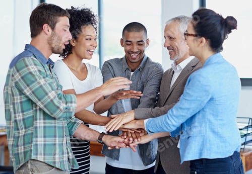 Preview: Shot of a group of happy coworkers standing with their hands together in huddle in an office