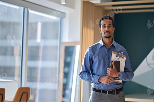 Preview: Young African American business man standing in office, portrait.