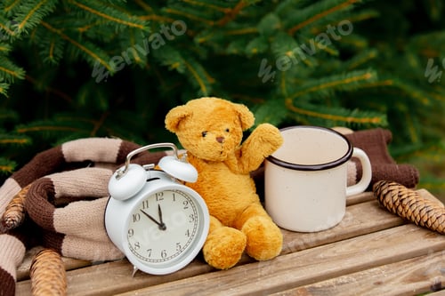 Preview: vintage alarm clock, teddy bear and cup of coffee on wooden table with spruce branches on background