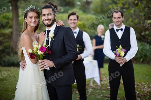 Preview: Wedding couple standing with bouquet of flowers in garden