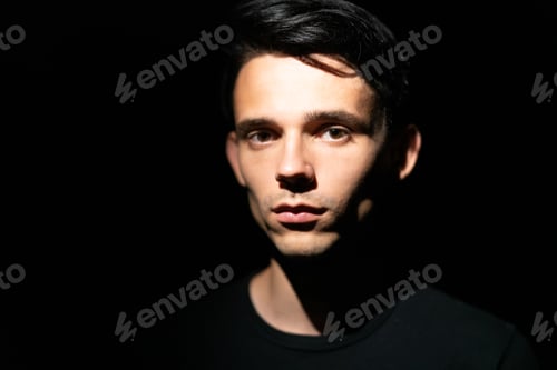 Preview: young guy on a black background in hard light, selective focus