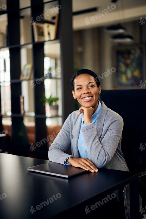 Preview: Smiling Professional Woman Sitting at Desk in Modern Office Environment
