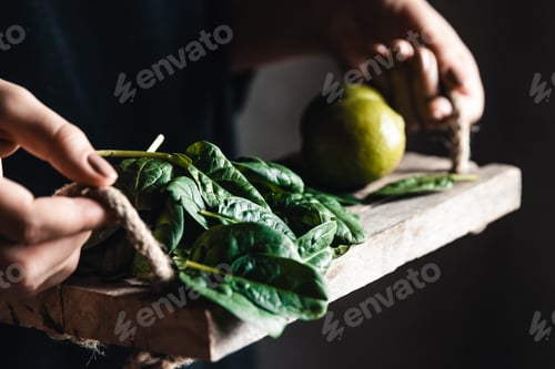 Preview: Girl holds on a vintage tray a spinach with lime. Vegan, wholesome food, eco