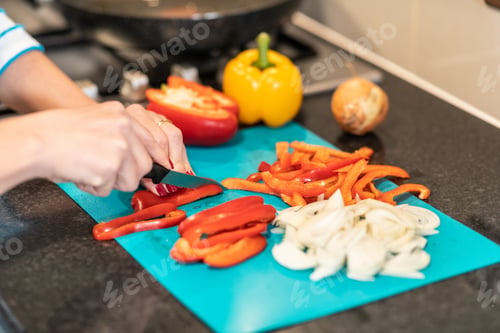 Preview: Woman slicing peppers in the kitchen preparing meal
