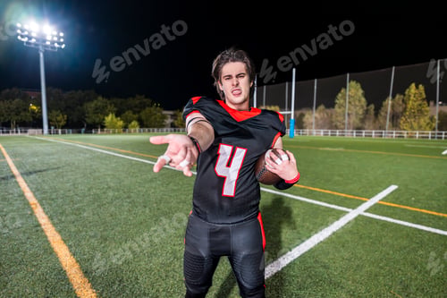 Preview: American football player taunting team on field at night