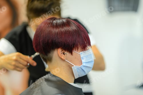 Preview: Closeup shot of a female getting her hair done wearing a face mask - concept of the new normal