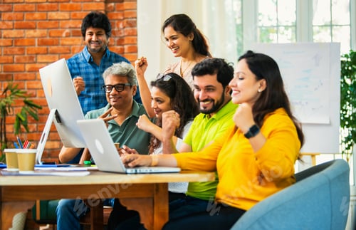 Preview: Young Indian entrepreneurs cheerfully celebrating success at a startup office after hard work