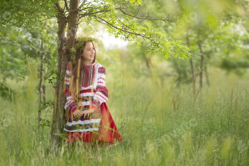 Preview: a girl in a Ukrainian folk costume, a white blouse with embroidery and a red skirt, walks in a field