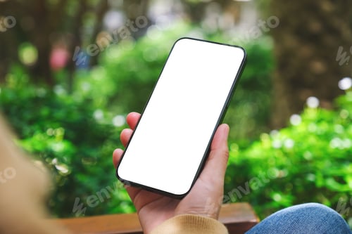Preview: Mockup image of a woman holding mobile phone with blank white desktop screen in the outdoors
