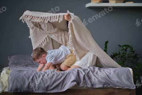 Preview: mom and child have fun in the bedroom on the bed, play under the blanket.