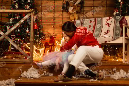 Preview: mother in a stylish sweater with a cute little daughter in a cozy room. Happy Christmas