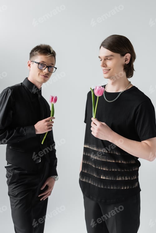 Preview: Positive gay couple holding tulips isolated on grey