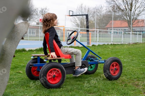 Preview: Young boy playing in a public park with his go kart push car