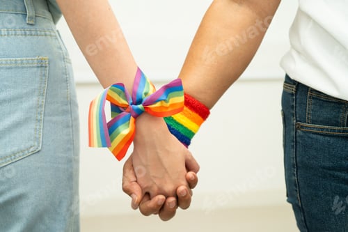 Preview: Asian LGBT couple woman holding hand wearing rainbow wristband.