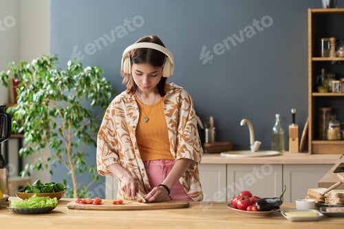 Preview: Teenage Girl Listening to Music While Slicing Vegetables in Kitchen
