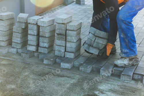 Preview: Workers installing concrete blocks on pavement in construction site during works day hours