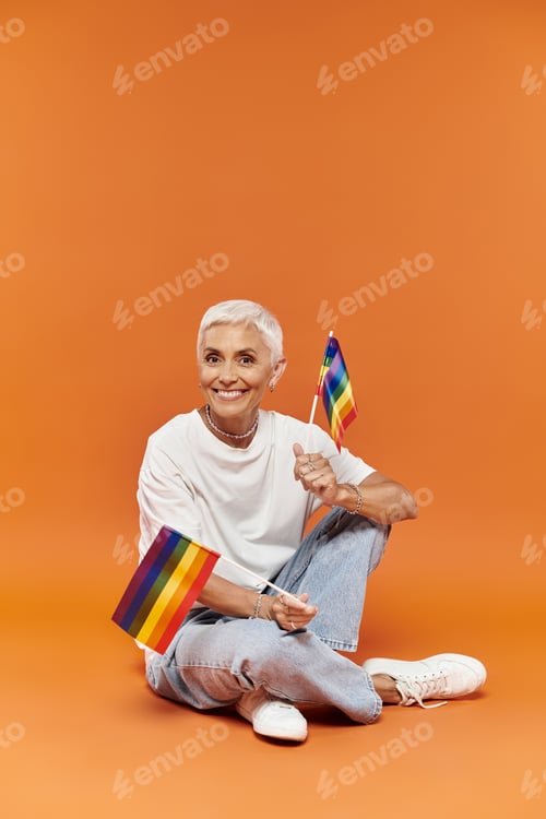 Preview: Confident Mature Lesbian Celebrating Pride in Stylish Outfit Against Orange Background