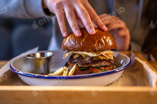 Preview: Close-up burger with egg and meat in a plate with sauce.