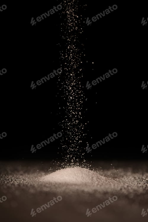 Preview: Salt is strewed on top of a hill of salt on the table. Black background.
