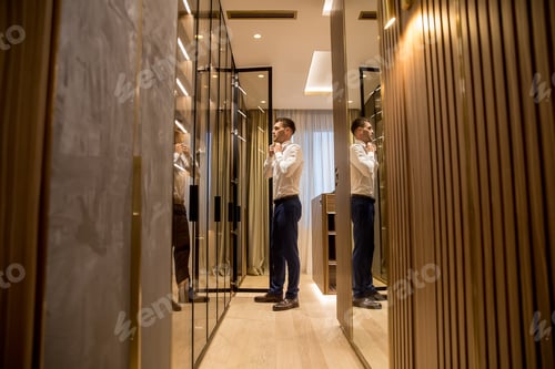 Preview: Young man choosing clothes from wardrobe in the hall of contemporary apartment