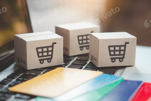 Preview: Shopping online. Credit card and cardboard box with a shopping cart logo on laptop keyboard.
