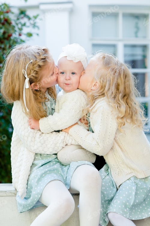 Preview: 3 little girls with light hair are hugging. Love of sisters.