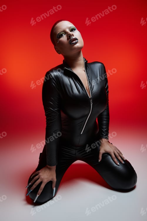 Preview: Young woman with pink hair and a nose piercing posing boldly in a vibrant studio