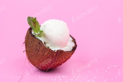 Preview: Vanilla ice cream balls in fresh coconut halves, decorated with mint leaves on a pink background
