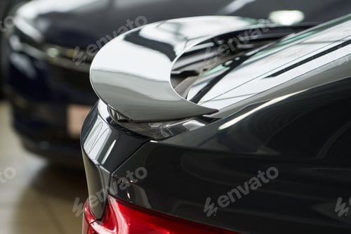 Visualização: no topo da asa traseira, uma visão rápida de um carro de alta velocidade de cor escura em um estado elevado de ativação