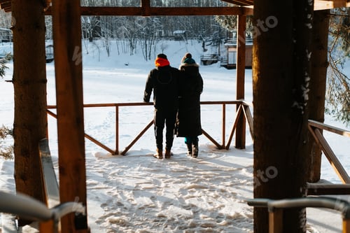 Preview: Young couple in love hugging on wooden gazebo, enjoying winter landscape outdoors, back view.