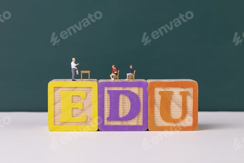 Preview: Teacher and student figurines standing on EDU wooden letter blocks