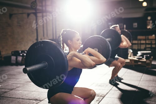 Preview: Man and woman lifting barbells at gym
