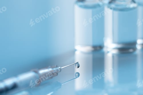 Preview: Closeup shot of covid19 vaccine bottles with a needle on a blue background - covid19 concept