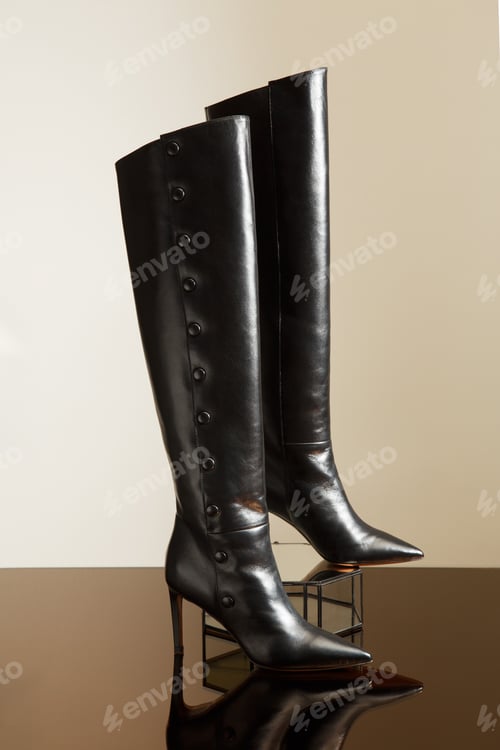 Preview: Closeup view of fashionable ladies high heel leather over the knee boots on glass stand.