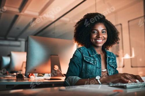 Preview: Low angle portrait of an attractive young female designer working on her computer in the office