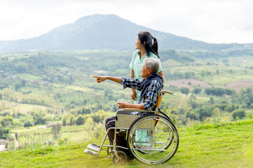 Preview: Asian nurse stand and look to the direction of senior man on wheelchair pointing and both near cliff