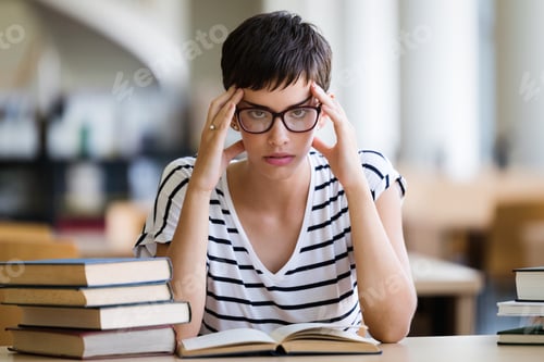 Preview: Young stressed student girl studying pile of books