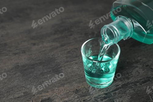 Preview: Pouring mouthwash in glass and space for text on dark background. Teeth care