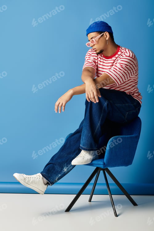 Preview: Young african american man showcases trendy style against a vibrant blue backdrop