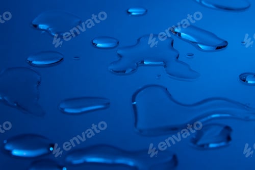 Preview: Drops of cosmetic substance on a blue background. Background image for a cosmetics store.