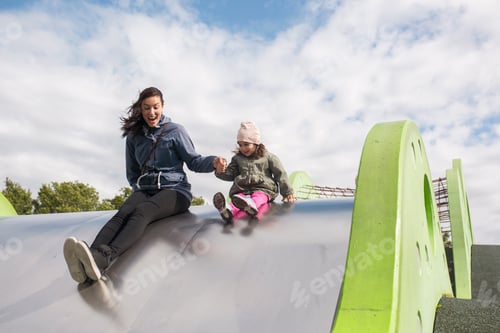 Preview: Mother with little daughter playing on outdoor slide