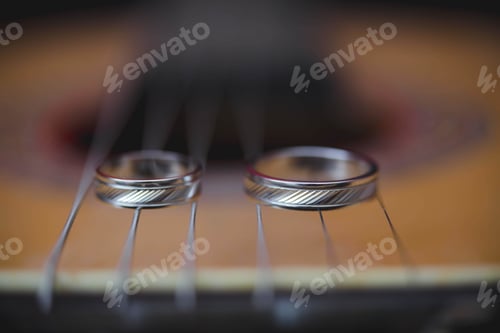 Preview: Selective focus shot of a couple of wedding rings on guitar strings