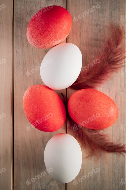 Preview: White and orange easter eggs on a light wooden background.